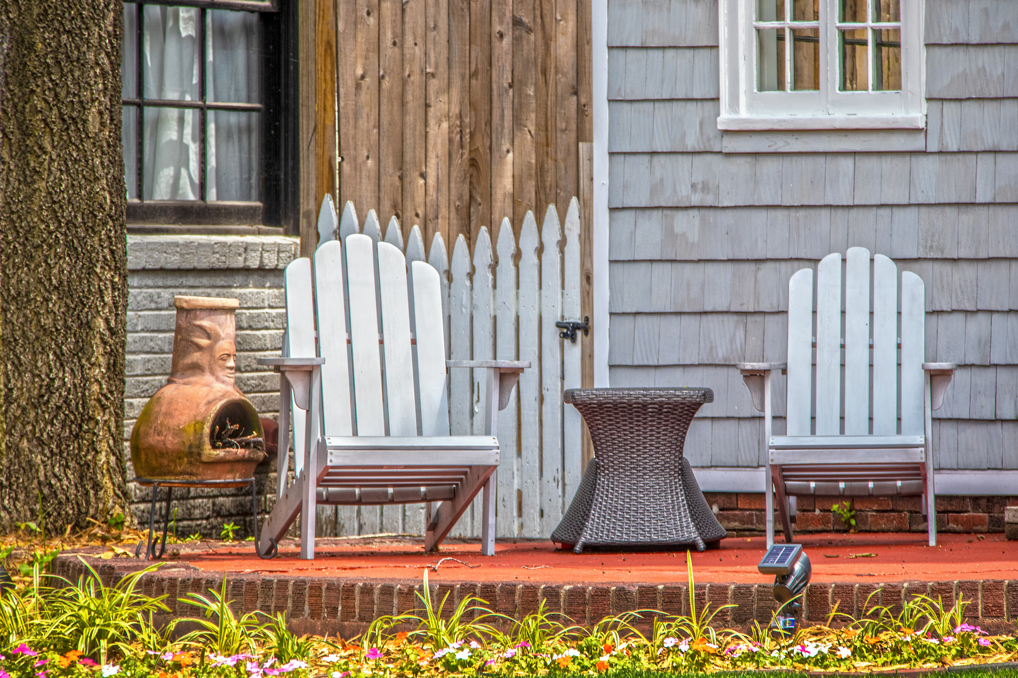 Two Adirondack chairs on a brick patio.