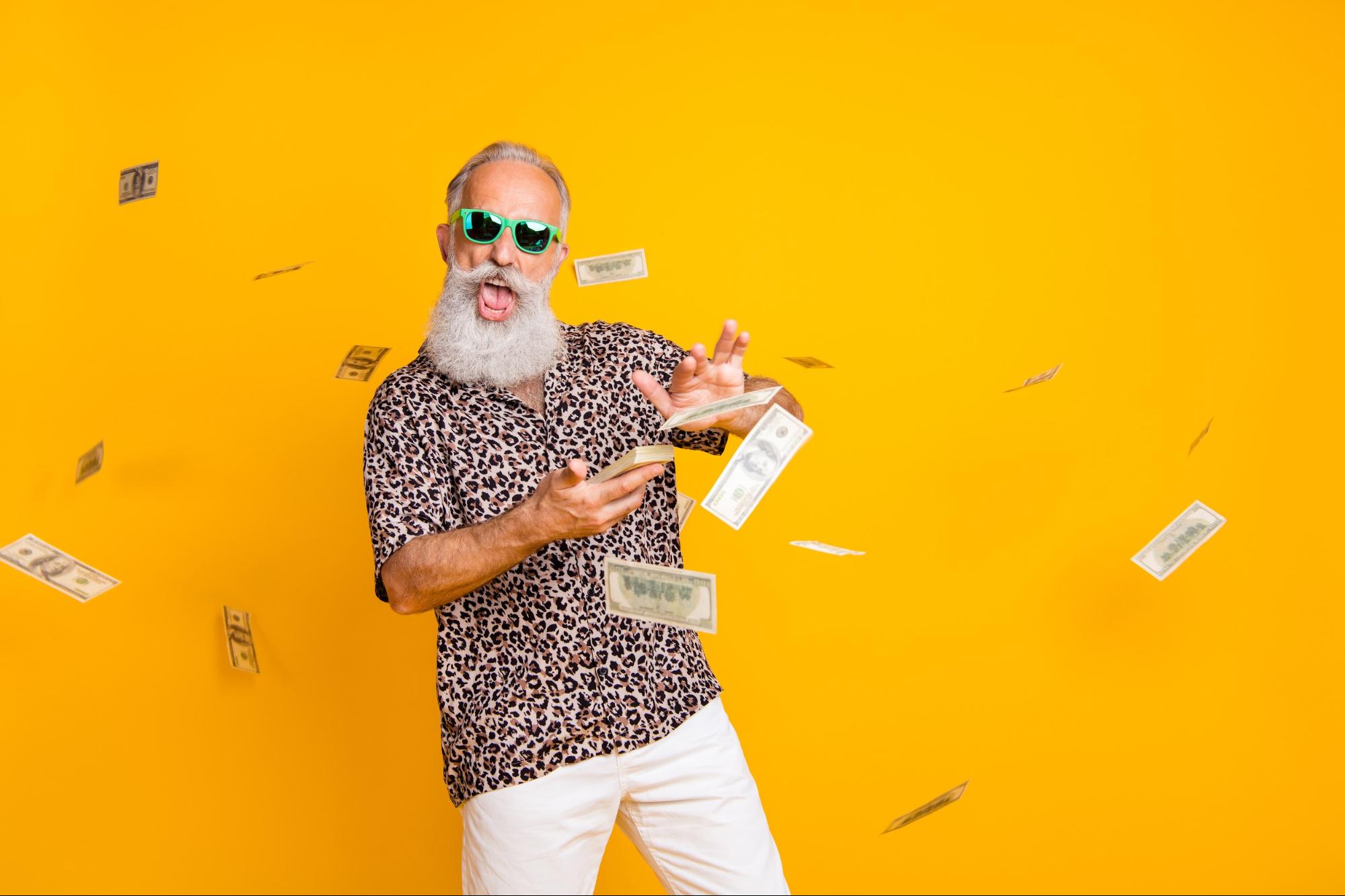 gray haired man throwing money on yellow background 
