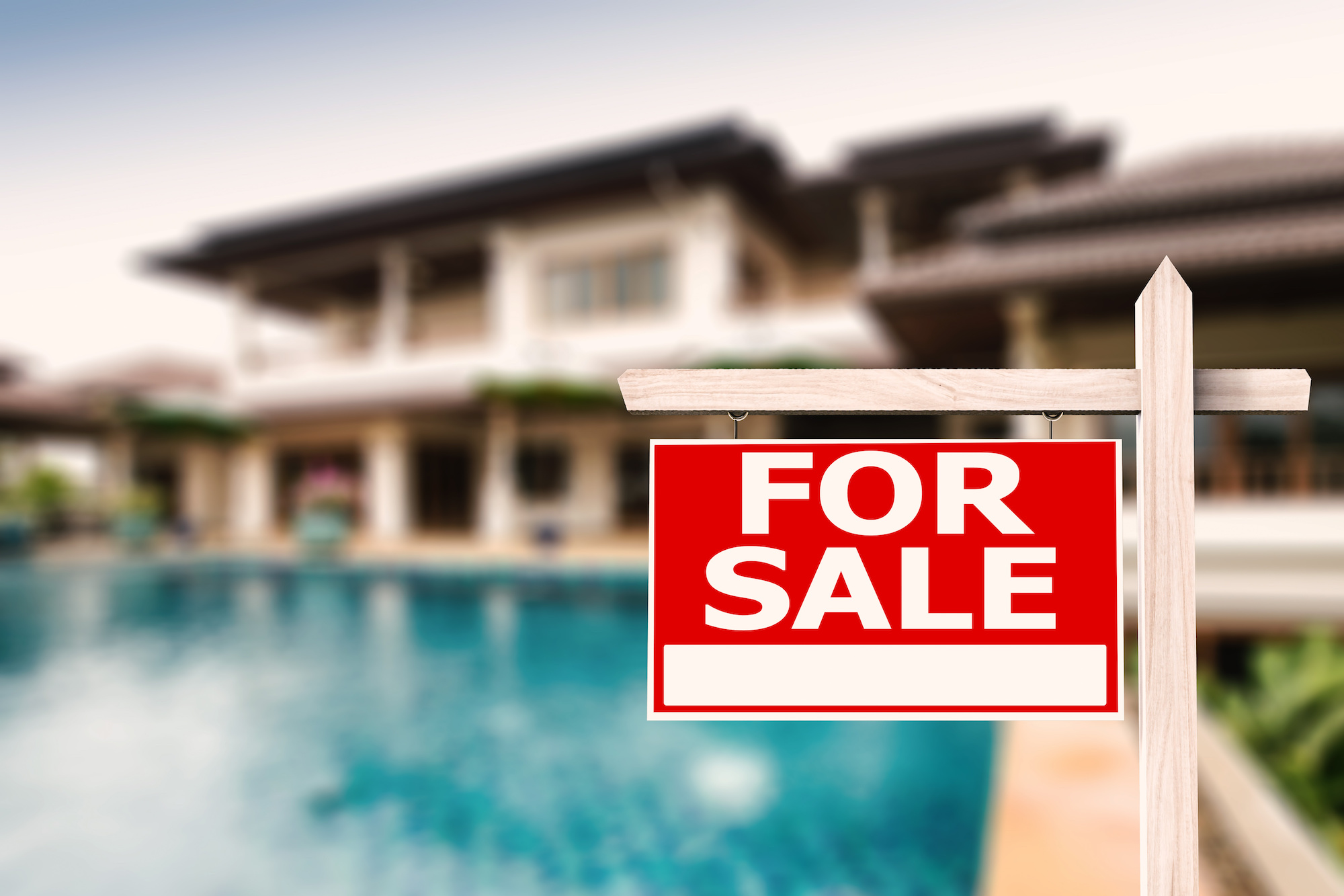 "For sale" sign in front of a house with a pool.