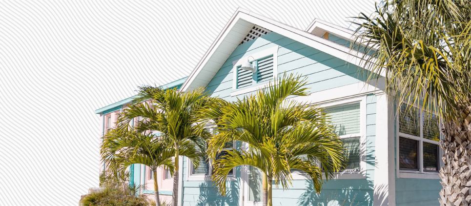 Light blue bungalow surrounded by palm trees. 