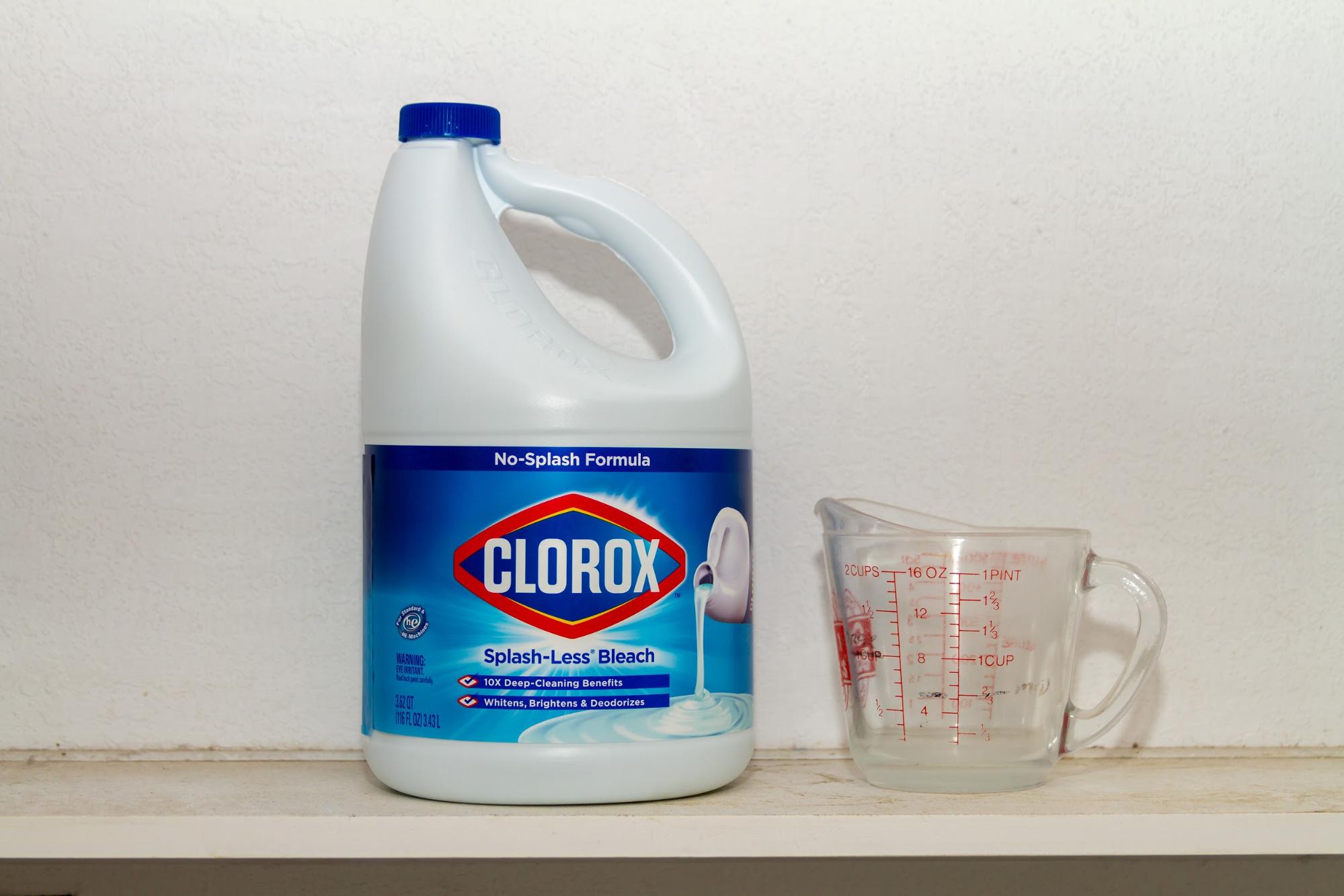 large bottle of bleach with a measuring cup 
