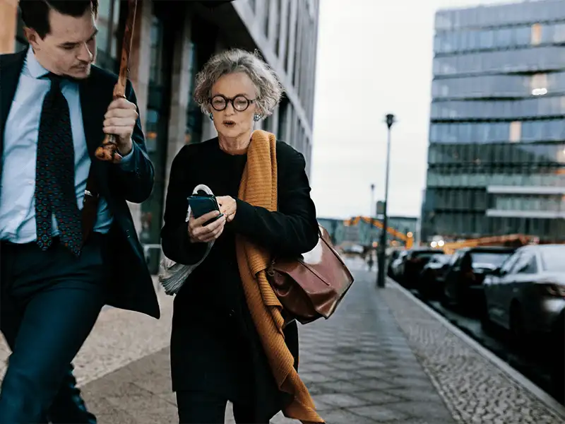 Woman and man walking down a city street looking at woman's phone
