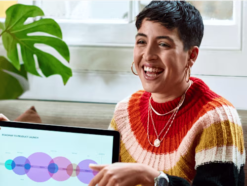 Persona con suéter colorido muestra un gráfico en una tablet sobre el lanzamiento de productos, relacionado con Docusign.