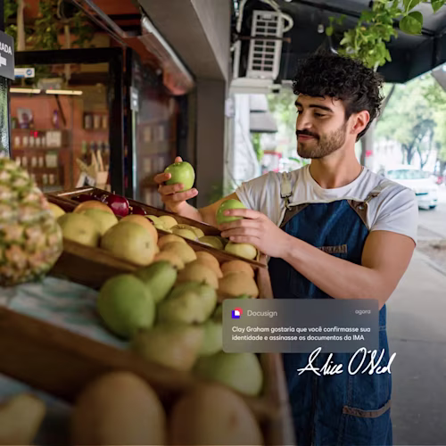 Pessoa com um telefone e um tablet, sorrido do lado de fora de uma pequena empresa