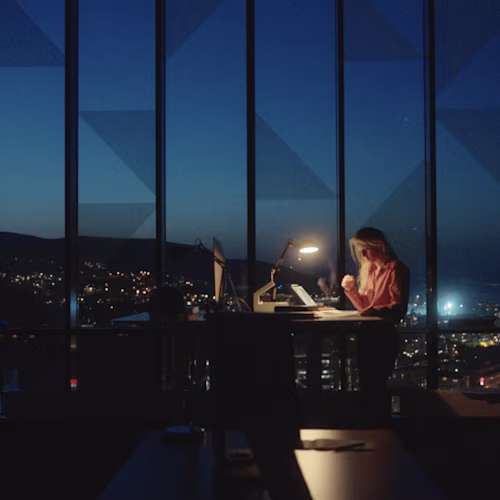 Woman working at a desk at night in front of a large window