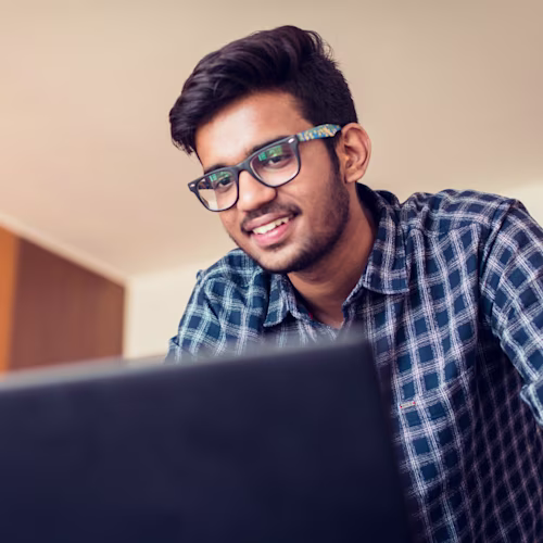 A man wearing glasses is standing in front of a laptop computer