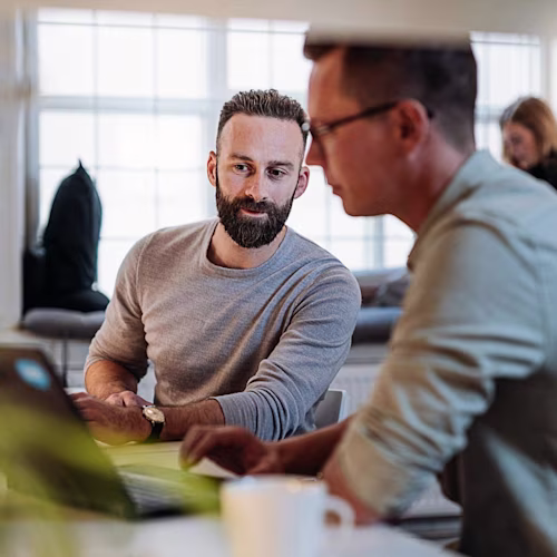 Een man die een bril draagt, staat achter een laptop