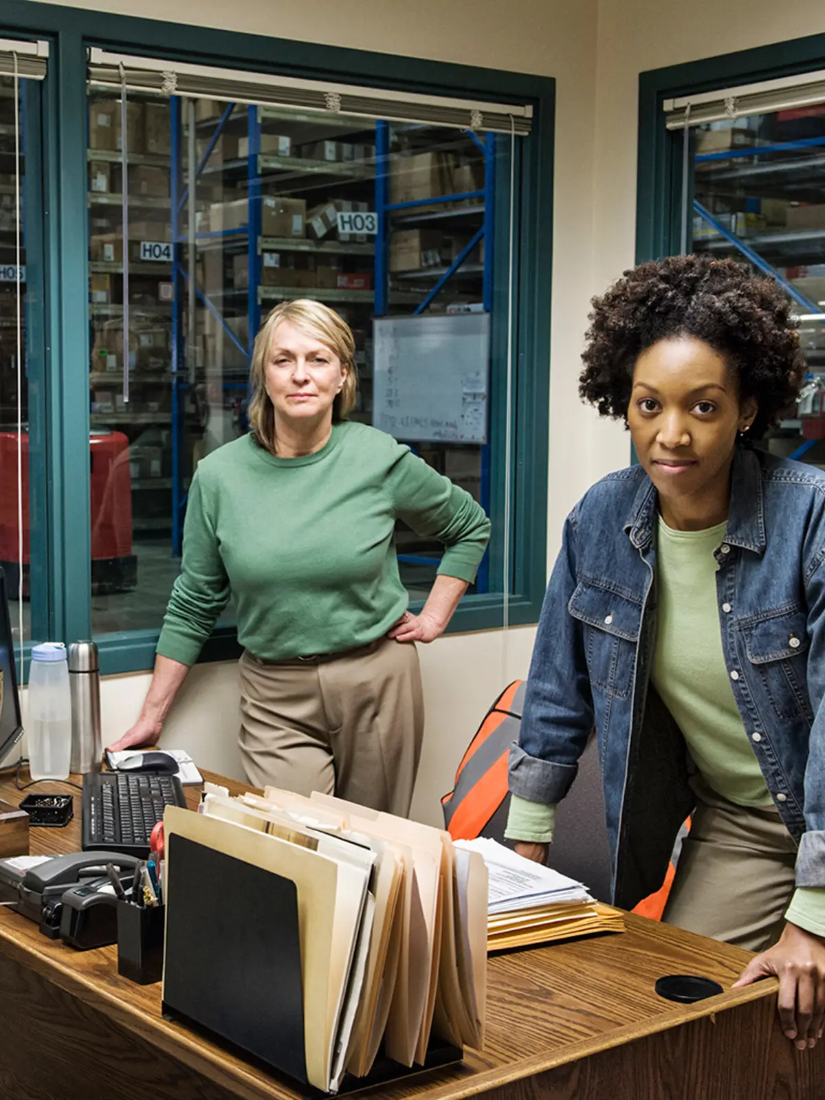 Two women discussing work in a large warehouse.