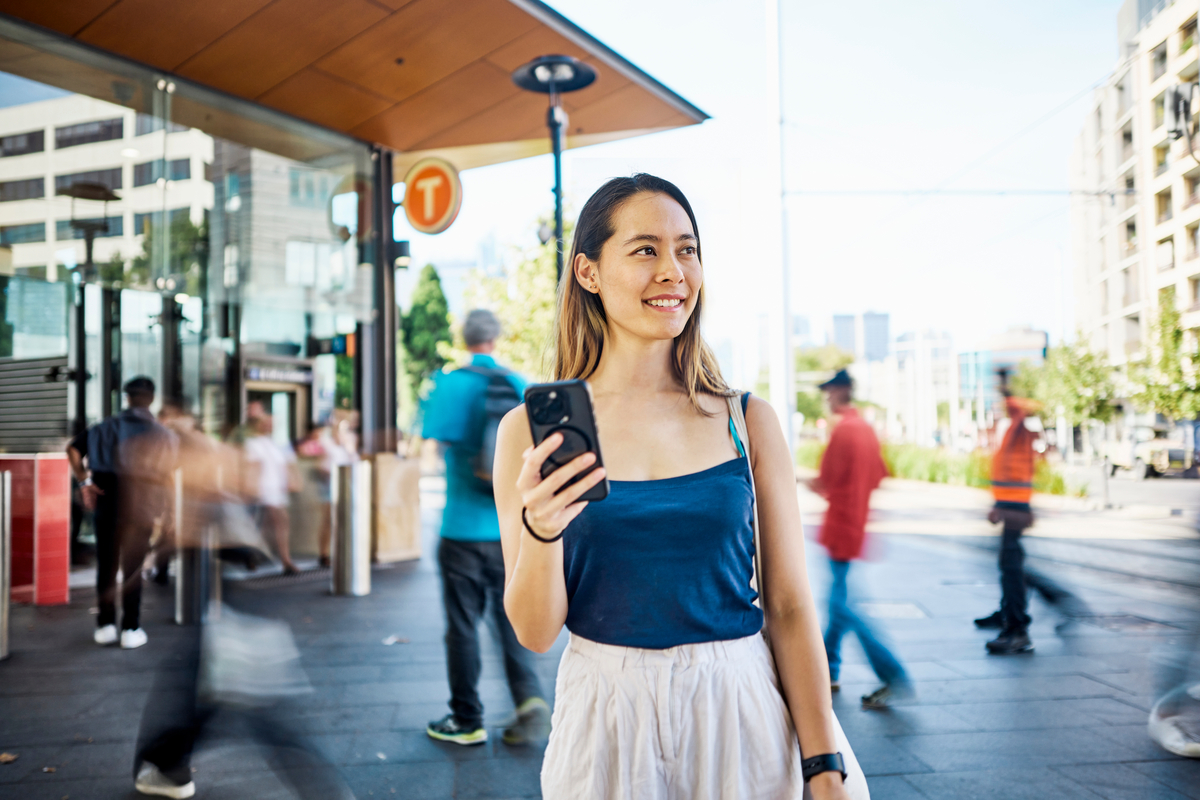 Una persona con una camisa azul está sentada en una mesa, escribiendo en una laptop con una taza de café cerca en un espacio de trabajo moderno.