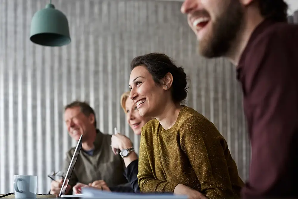 Collègues souriants assis atour d'une table dans une salle de réunion