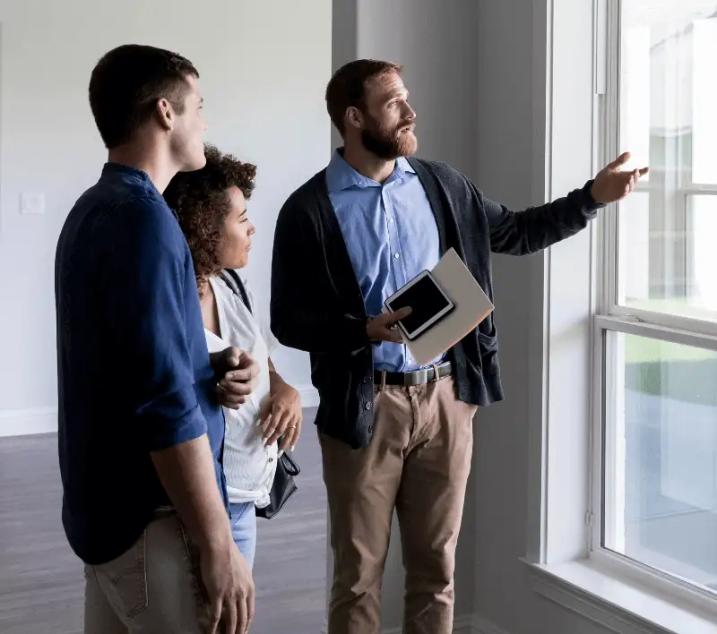 Real estate agent shows a couple the view out a window.