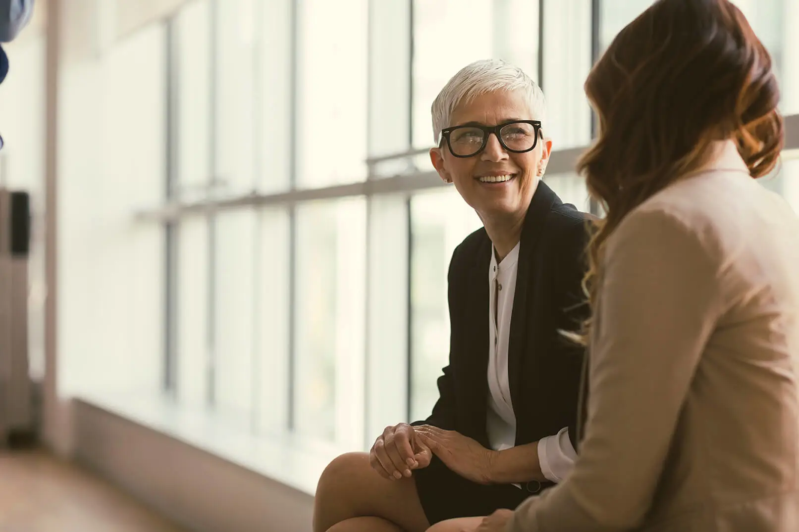 Two businesswomen sitting next to each other chatting 