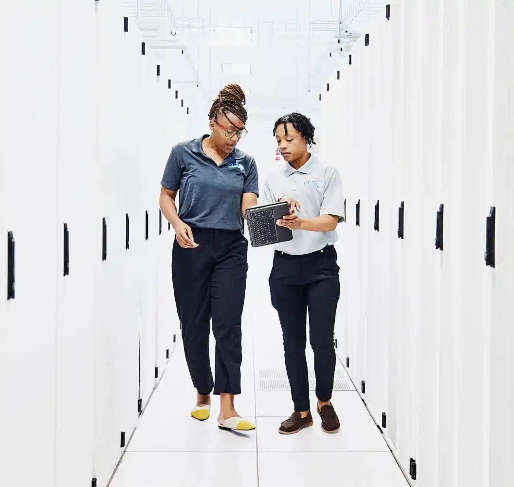 Vrouwelijke IT'ers bekijken gegevens op een digitale tablet in een datacenter.