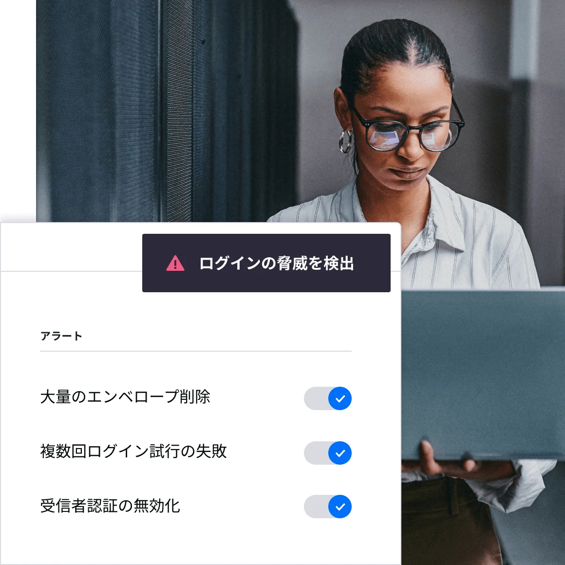 DocuSignが不正ログインの可能性を検知したことを知らせるアラート画面表示が、ラップトップを覗き込んでいる女性の上に重なっている