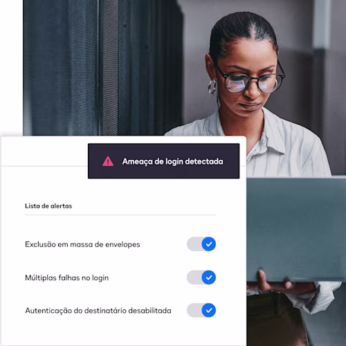 Uma tela com um alerta de detecção de ameaça de login da DocuSign aparece em cima da imagem de uma mulher olhando para um laptop