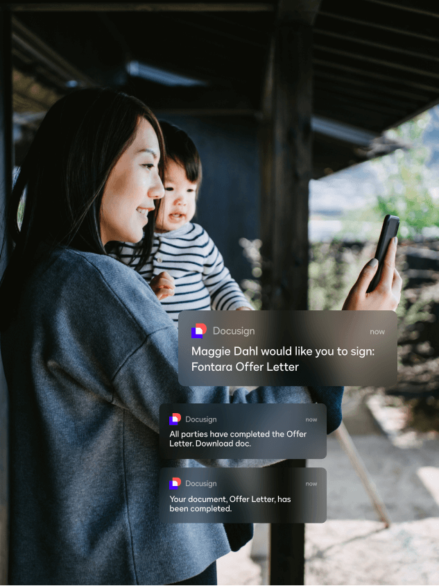 A woman standing in an office building and looking at her phone sees mobile notifications for DocuSign eSignature