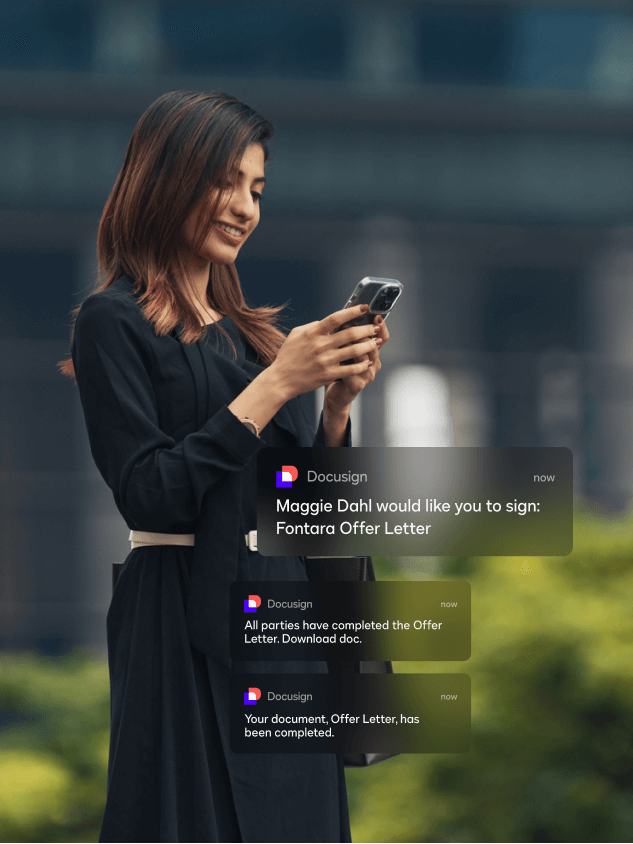 A woman walking outside and looking at her phone sees mobile notifications for DocuSign eSignature