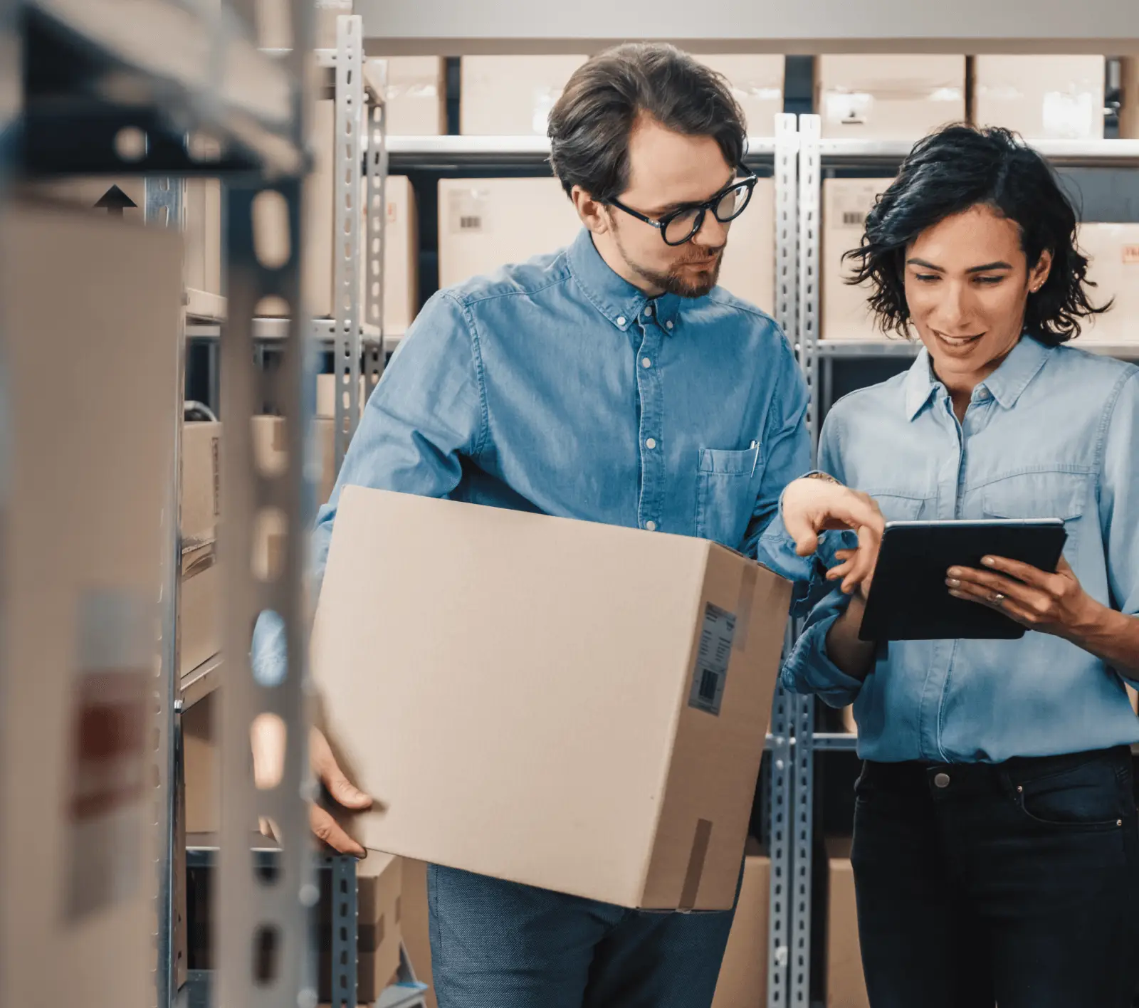 Two employees working in retail in a back office with boxes look at a retail contract on a tablet