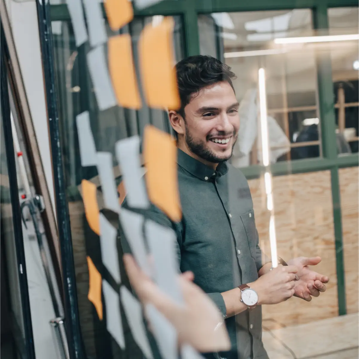 A man in an office holding a pen and talking to a coworker