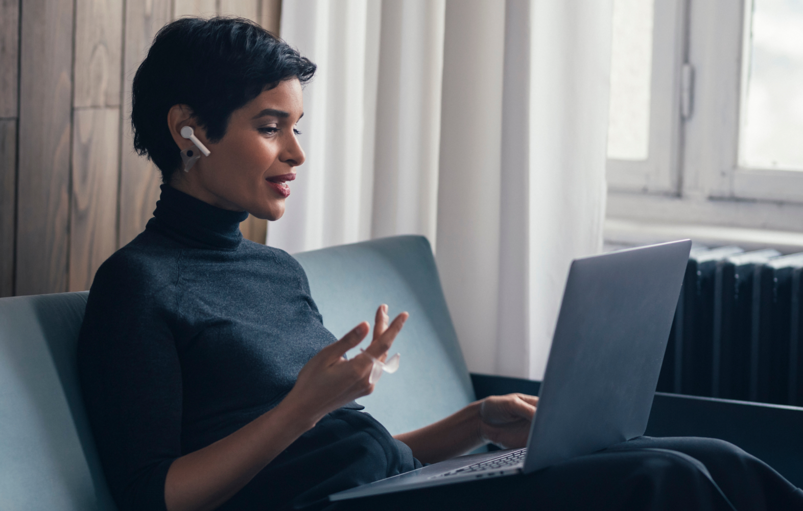 Une jeune femme d'affaires utilise son ordinateur portable et une paire d'écouteurs sans fil pour passer un appel vidéo.