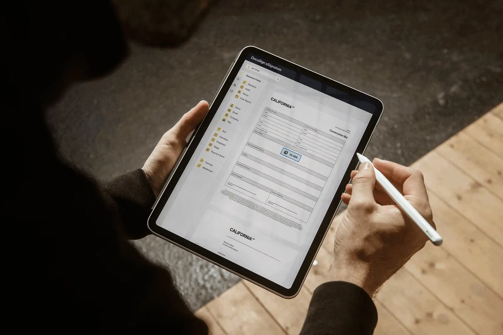 A person fills out a form on a tablet with a stylus