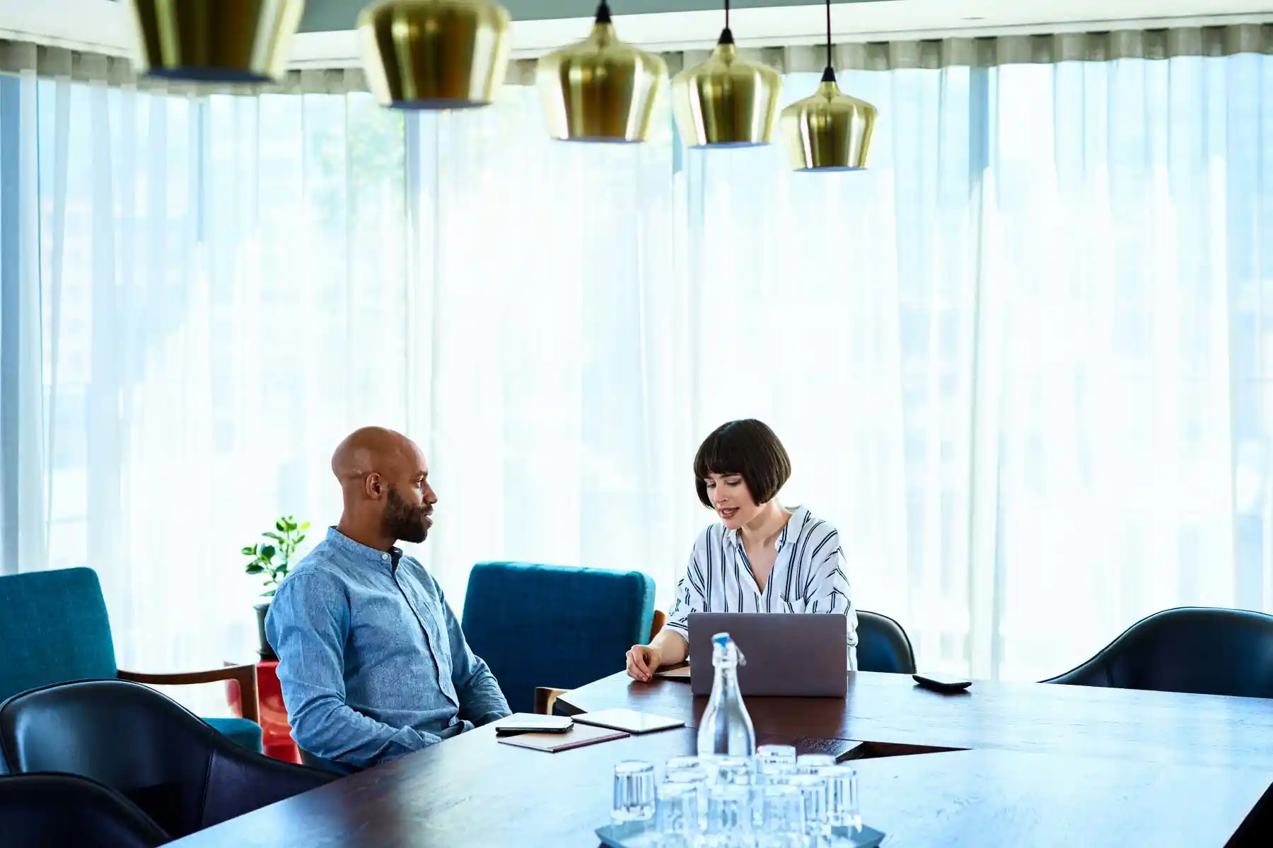 Two employees having a discussion in a conference room.