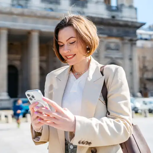 A woman is standing in front of a building looking at her cell phone

