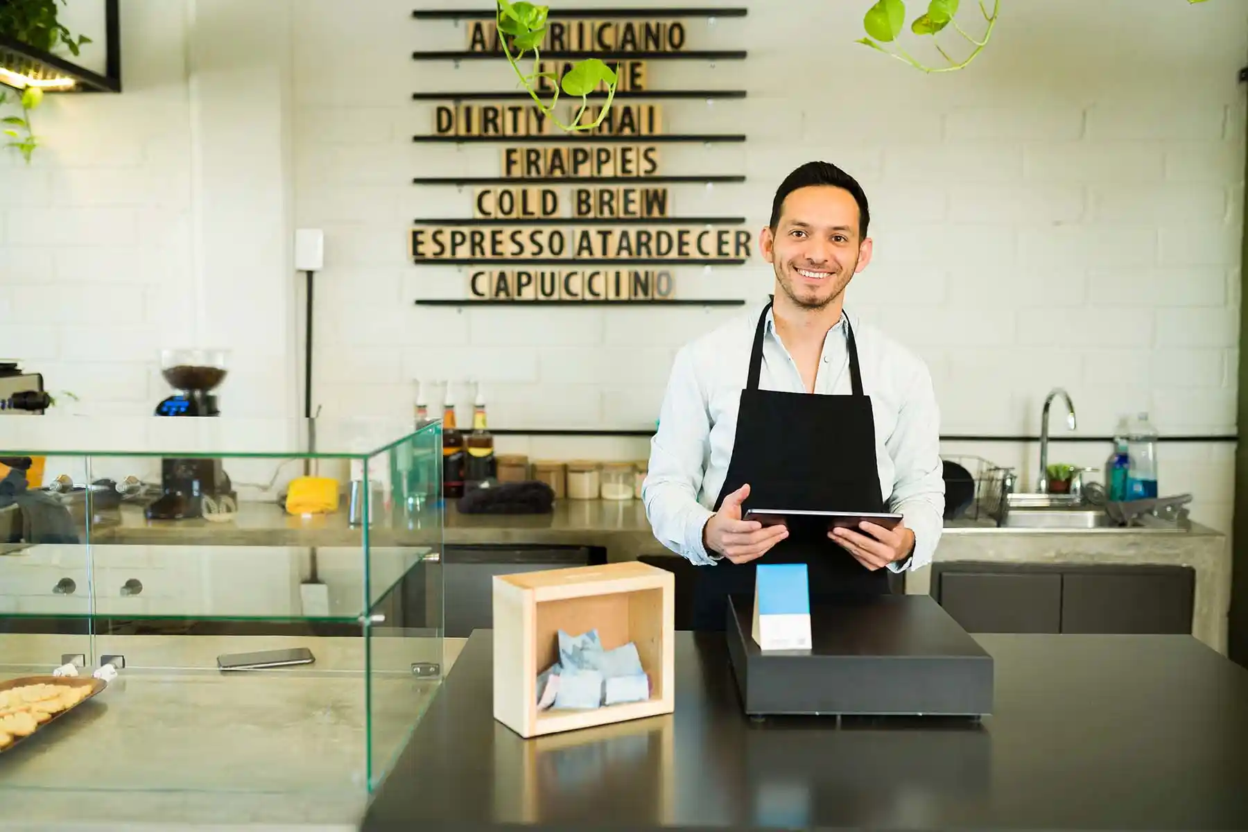 Un barista de pie en su mostrador de servicio.