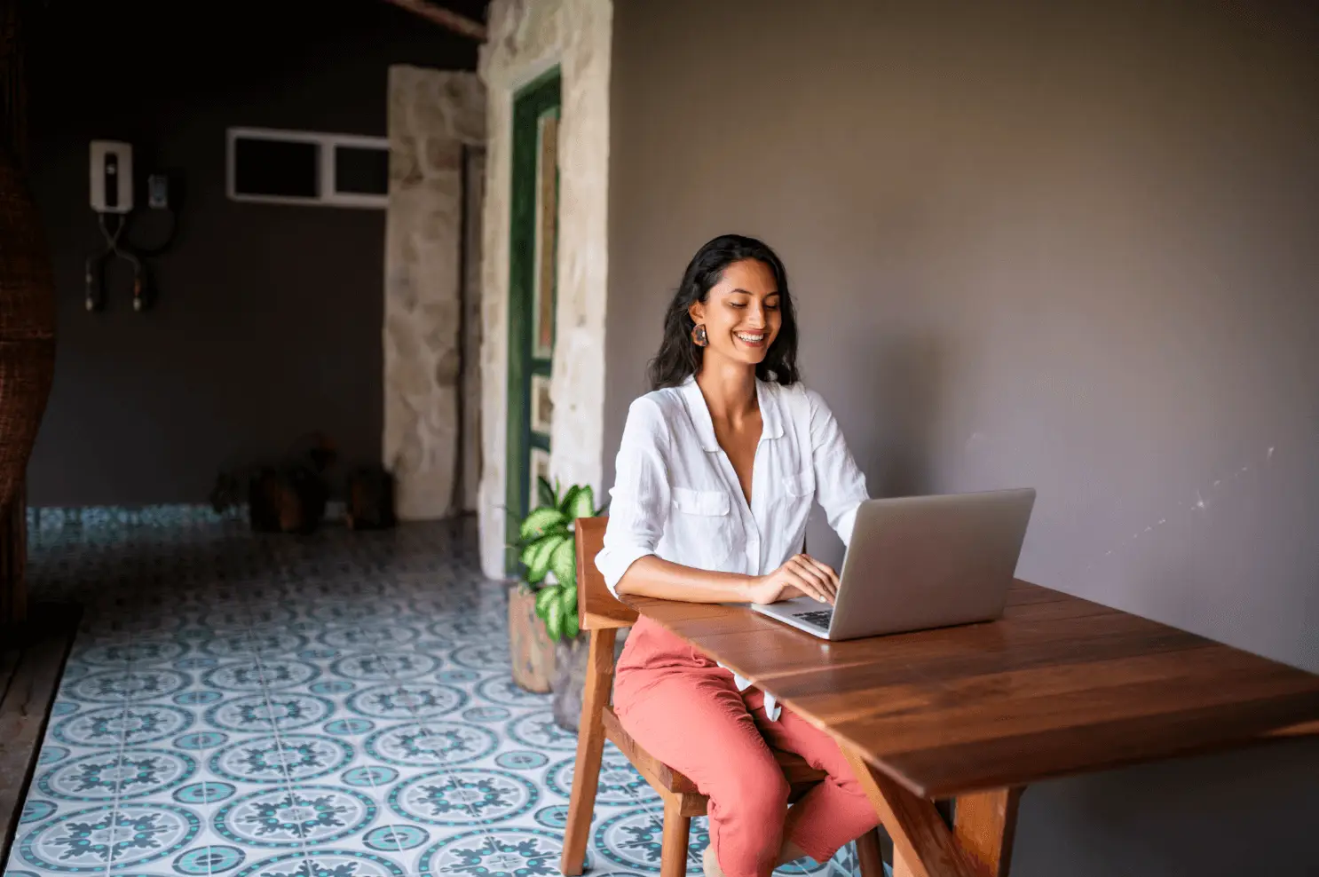 Person outside typing on a laptop smiling