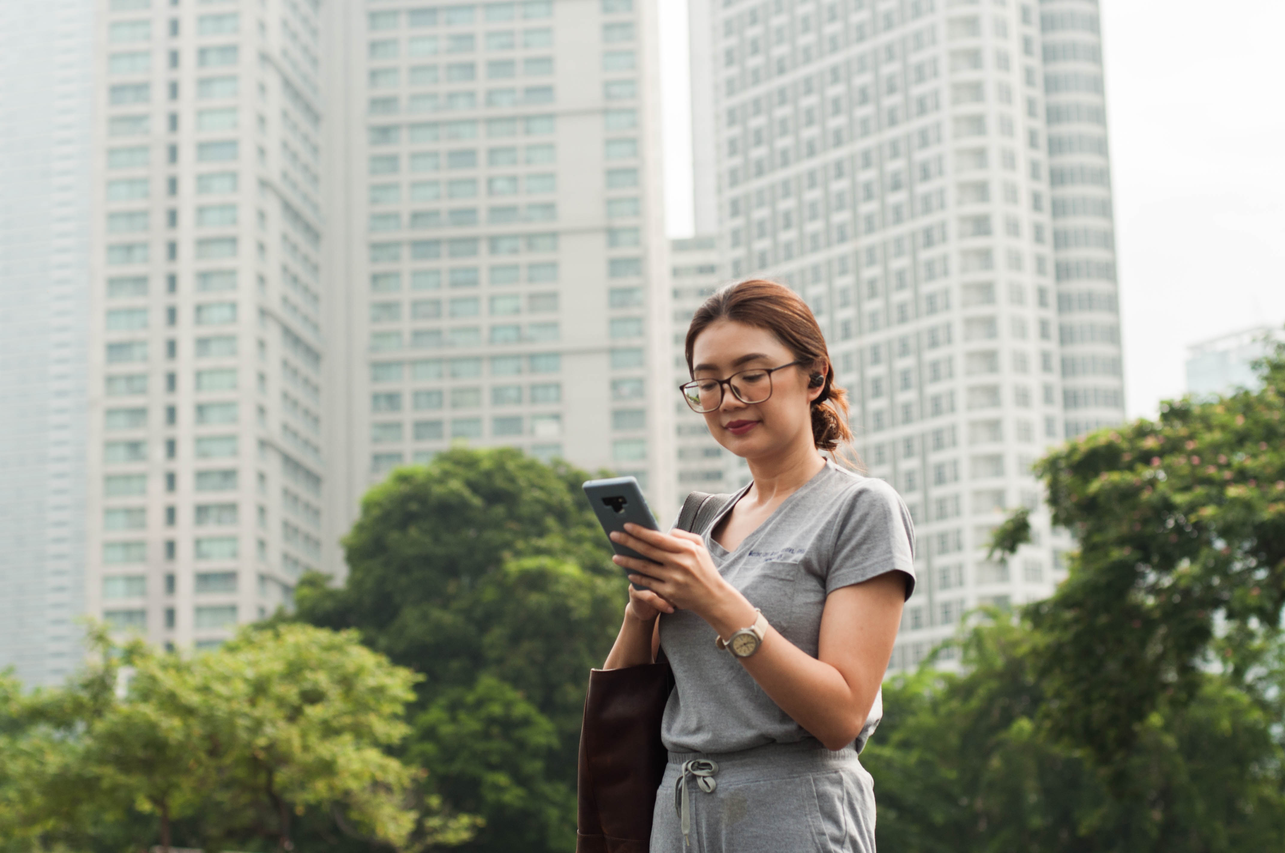 Woman on phone standing infront of office buildings