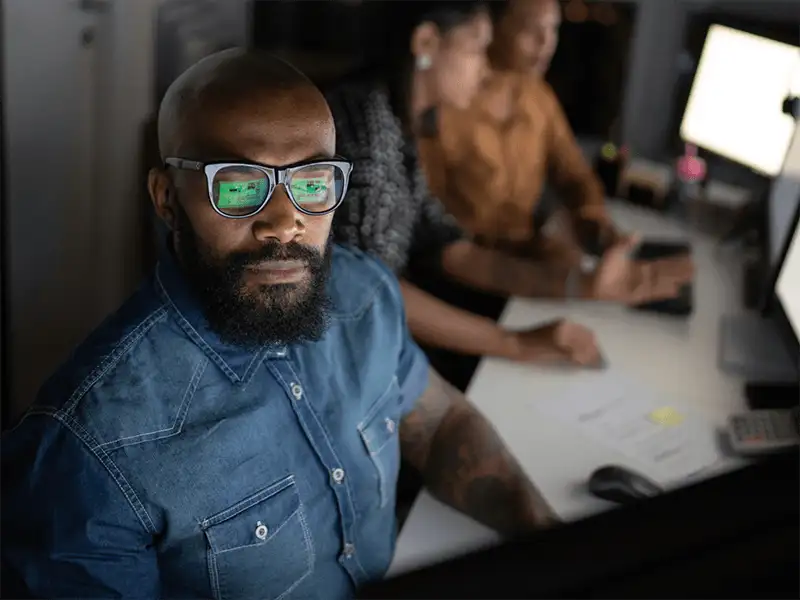 Business man looking at his computer screen next to two coworkers