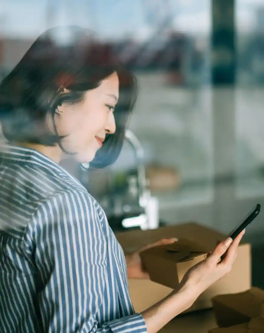 Glimlachende vrouw die aan het aanrecht staat en eten bestelt met een smartphone.