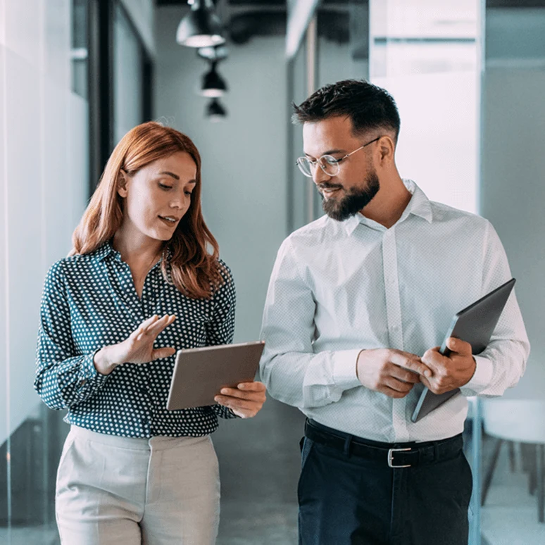 Woman and man walking and looking at a tablet