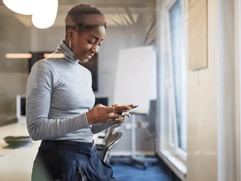 Geschäftsfrau am Arbeitsplatz überprüft ihr Telefon