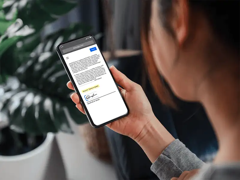 Woman holding phone with screen showing a document signed with DocuSign