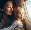  Γυναίκα και νήπιο κάθονται δίπλα σε παράθυρο αεροπλάνου και χαμογελούν. ​
