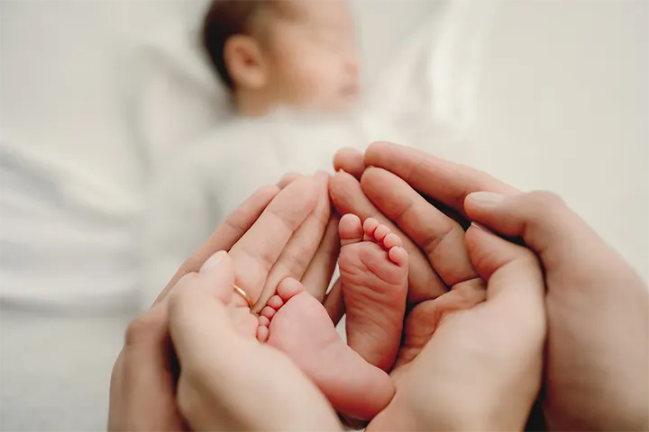 Μωρό κοιμάται και τα χέρια των γονιών πιάνουν τα ποδαράκια του
