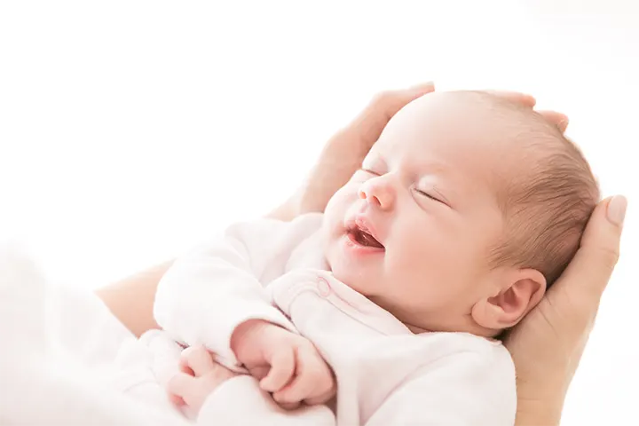 Χέρια κρατάνε το κεφαλάκι του μωρού που κοιμάται