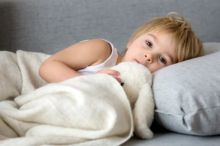  Νήπιο ξαπλωμένο σε καναπέ με κουβέρτα και λούτρινο παιχνίδι​