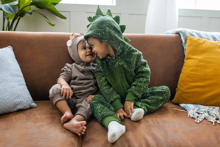 Μωρό και νήπιο στον καναπέ, ντυμένα με στολές ζωάκια​