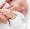 Μωρό ξαπλωμένο, κοιμάται και ακουμπάει το χέρι του γονιού