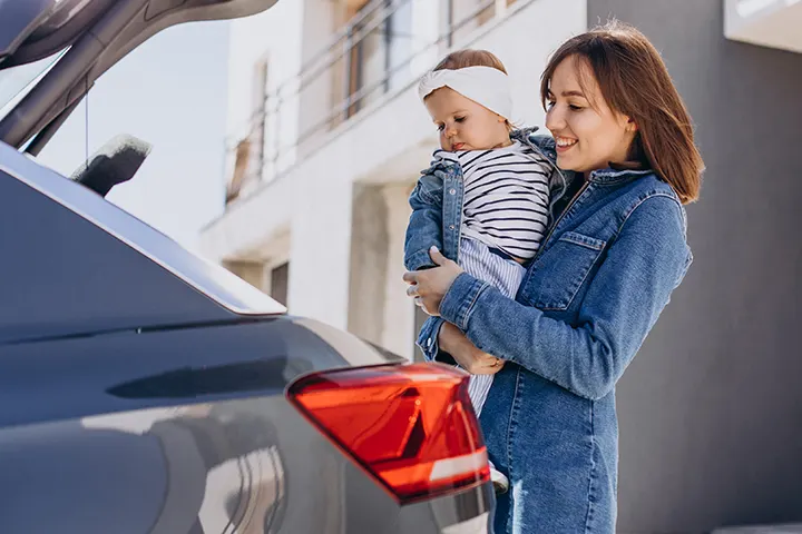 Μητέρα με μωρό αγκαλιά δίπλα σε αυτοκίνητο
