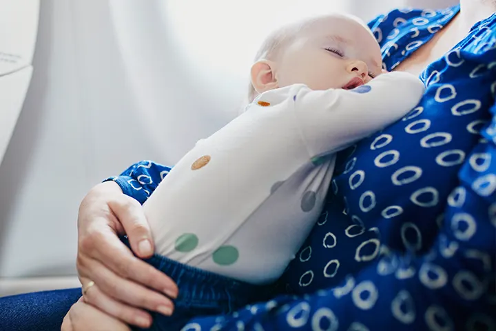  Μωρό κοιμάται στην αγκαλιά γυναίκας, σε καμπίνα αεροπλάνου.​
