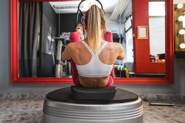 Woman sitting on vibration plate