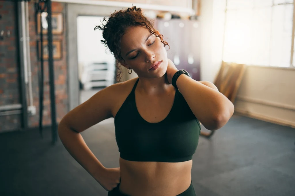Woman holding neck in gym