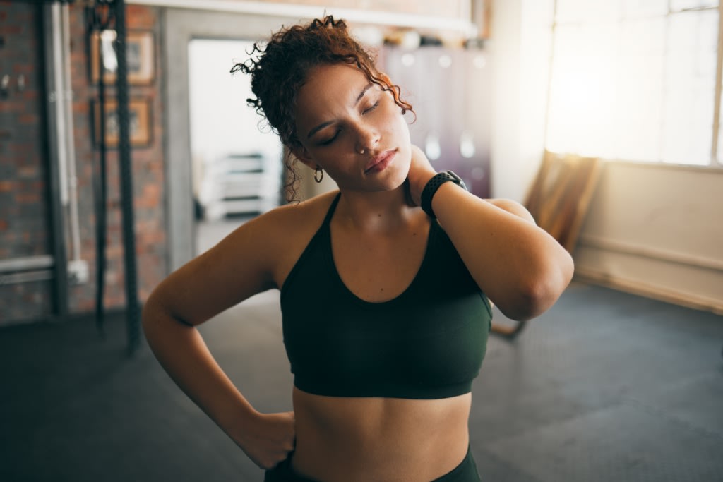 Woman holding neck in gym