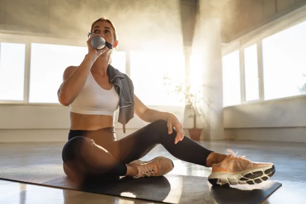 Woman drinking from bottle on yoga mat