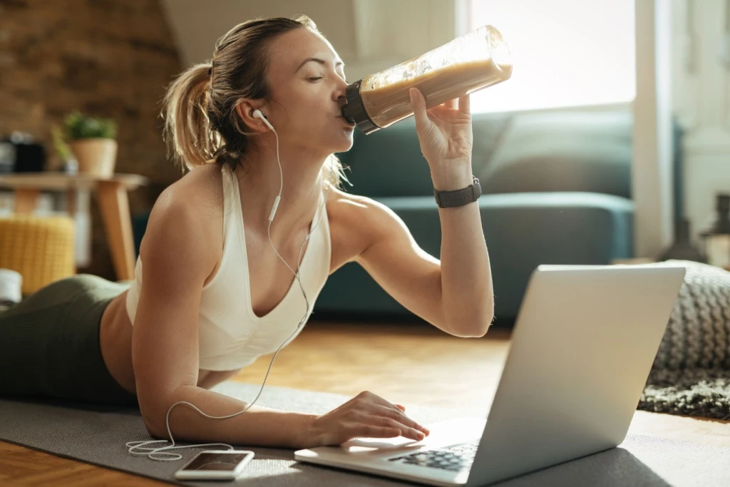 Woman on laptop drinking smoothie