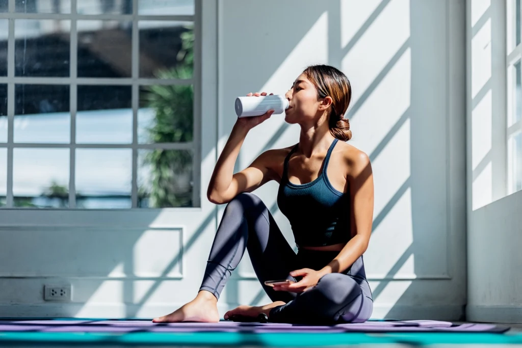 Woman drinking from bottle on mat