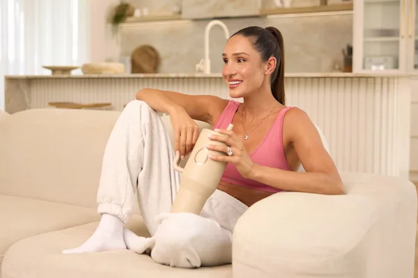 Kayla Itsines sitting on couch with drink bottle